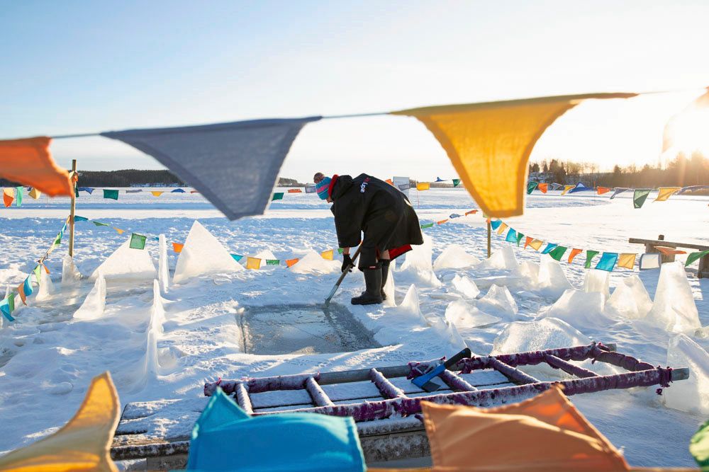 Dan sågar upp en isvak ute på Tavelsjön, säkerhetsmarkerad med färgglada vimplar.