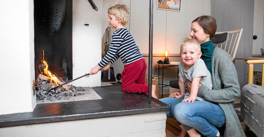 Frans och Helmer myser med mamma Elin framför den öppna spisen i allrummet.