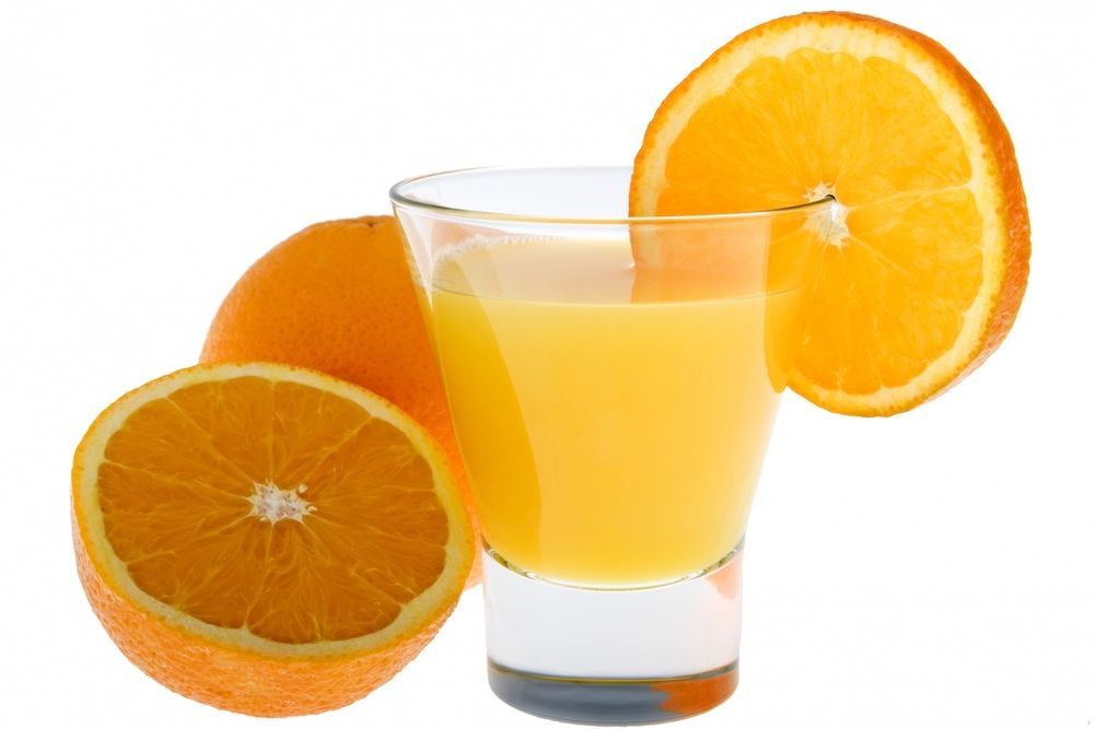 Glas med apelsinjuice omgiven av färska apelsiner