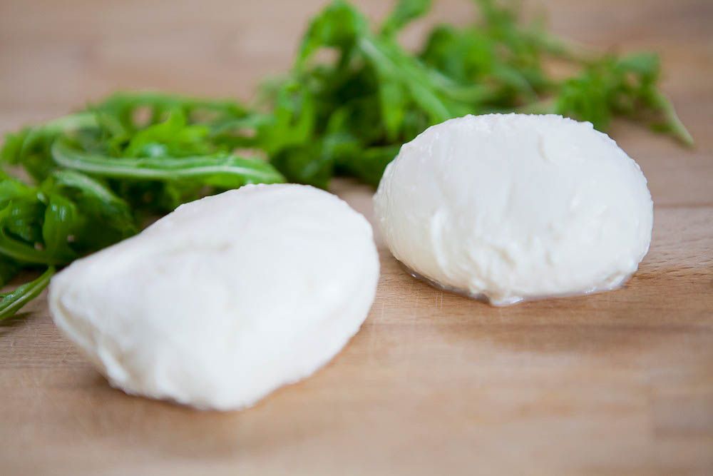 Två bollar mozzarella ligger på en skärbräda.