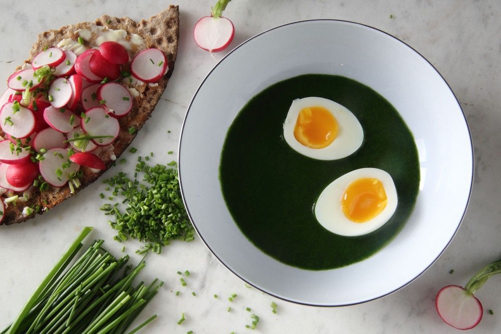 En skål med nässelsoppa med smakkompisar som ägg och gräslök.