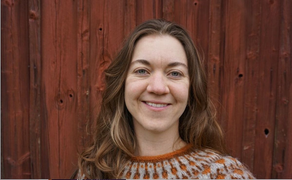 Leende kvinna framför en röd trävägg