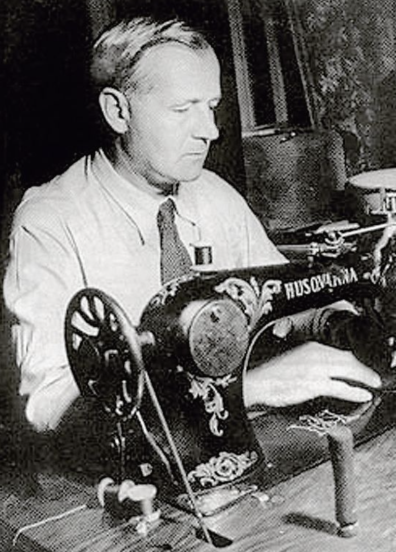Man i svartvit bild syr vid en gammaldags Husqvarna-symaskin