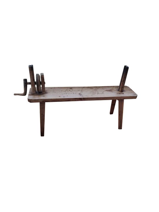 Gammalt träredskap på bänk med vev och runda träskivor