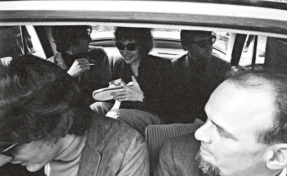 ”1966 var det presskonferens med Bob Dylan på Fredman i Solna. Efteråt stack jag ner kameran genom takluckan när Dylan skulle åka i väg och tryckte av. Kanske fick jag den sista bilden på när Dylan skrattar. Längst fram till höger syns Simon Brehm, som hade grammofonbolaget Karusell. Lasse Berghagen syns inte på bilden men han körde bilen – Lill-Babs Mercedes som de hade lånat!”
