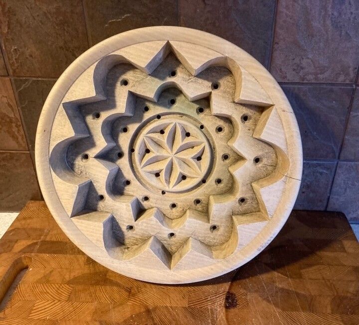 Runt träblock med snidad, geometrisk stjärndekor och små borrade hål