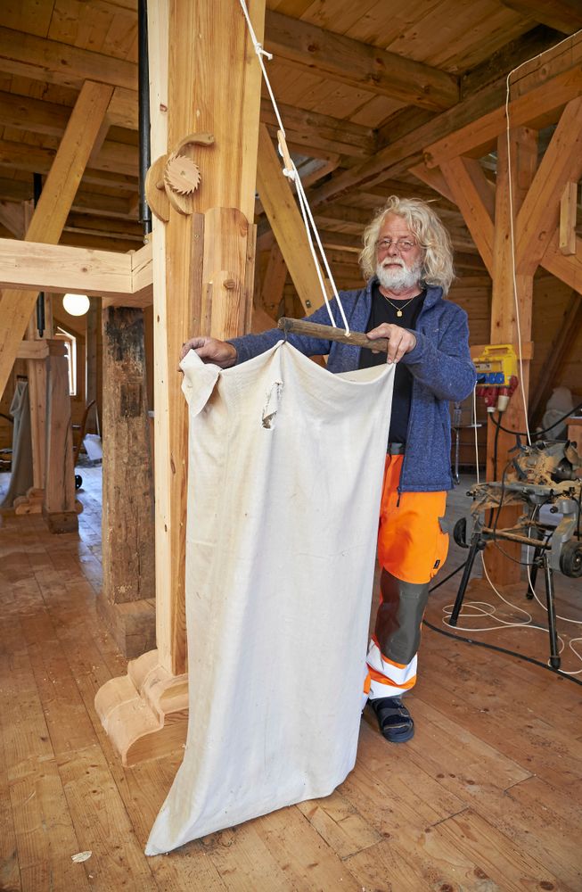 Ulf visar hur det nymalda mjölet ska rinna ned i rena jutesäckar.