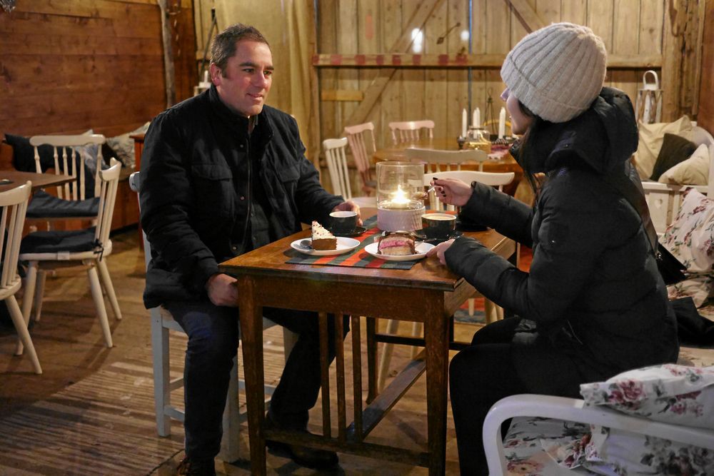 Stamgästen Gustaf fikar med dottern Michelle i kaféet i ladan. På vintern när det är kallt stängs dörren och tända ljus som lyser upp och värmer i den mörka ladan.