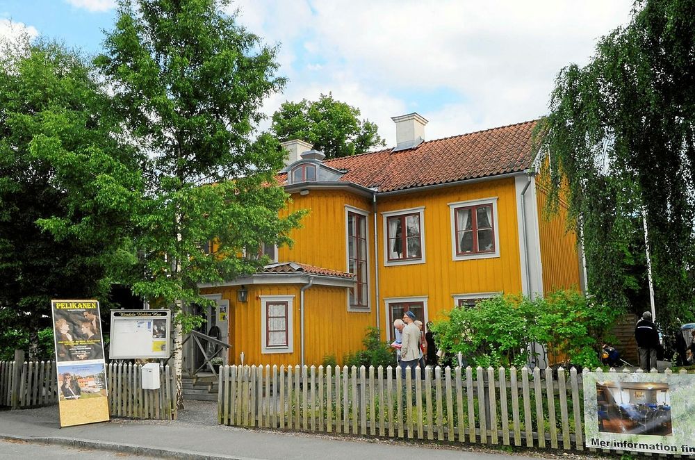 Människor ses köa utanför den gula villan inför ett teaterbesök. 