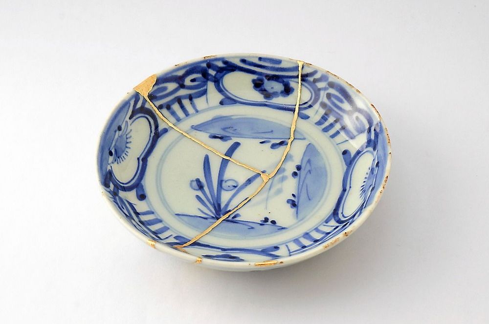 Kintsugi blå och vit assiett. Restaurering av sprickor på gammal japansk keramik restaurerad med den antika Kintsugi-restaureringstekniken. 