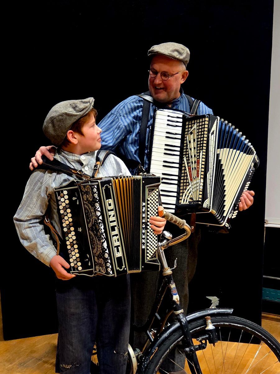 Pojke och man med dragspel står vid en cykel och ler mot varandra