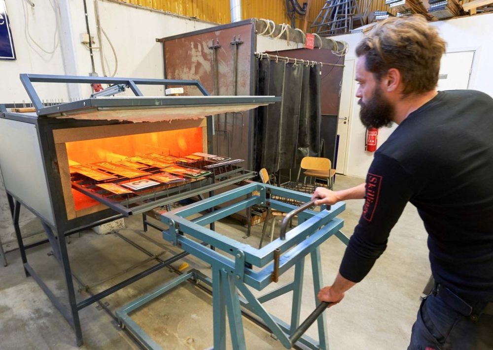 Fredrik Trane kör in emaljskyltar till sista bränningen i den 820 grader varma ugnen.