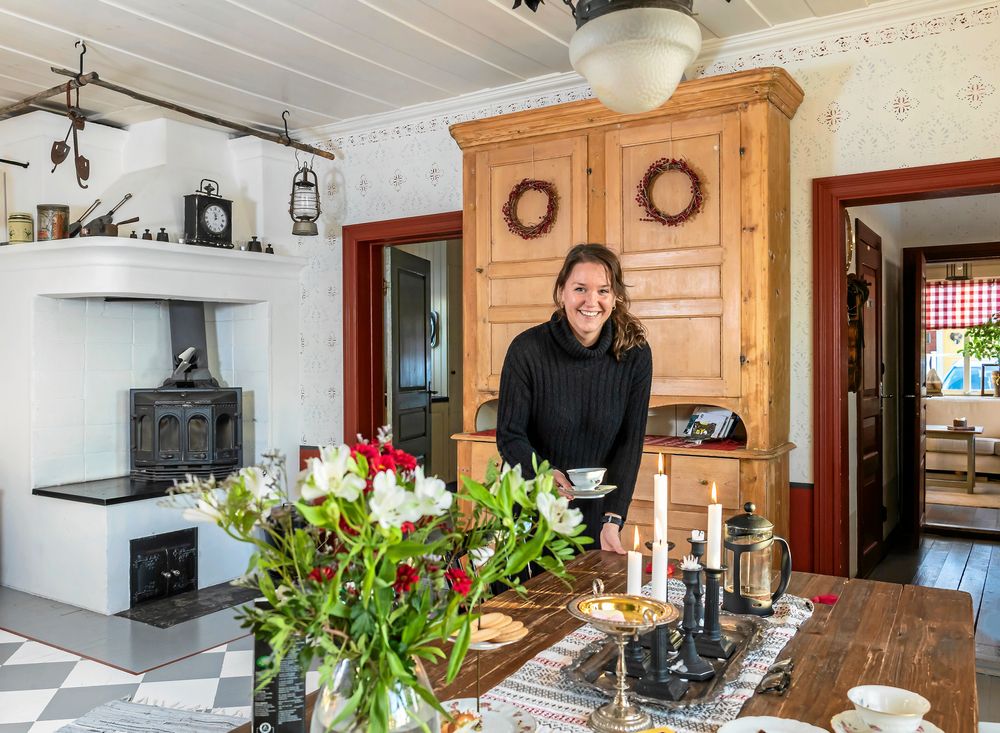 Erica i familjens favoritrum, det stora allrummet med öppen spis, rejäla matbord och rutmålade trägolv.