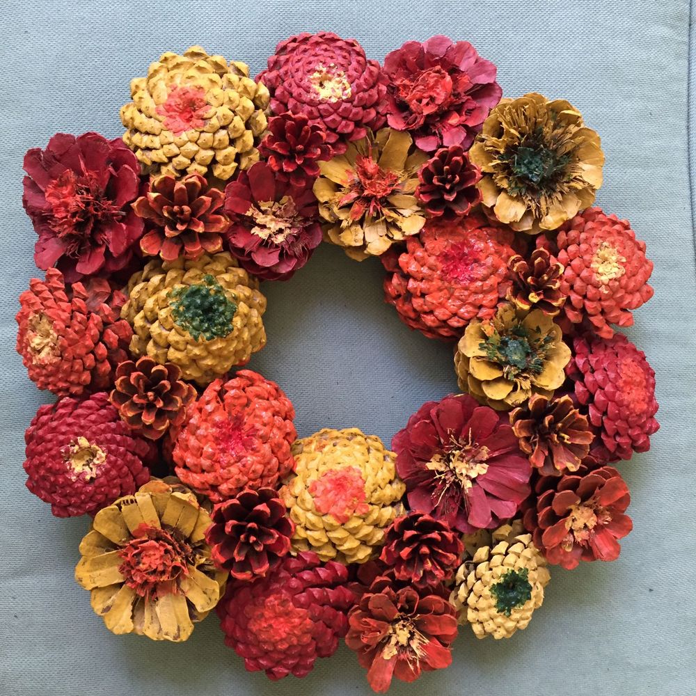 Krans av torkade kottar och blommor på blå bakgrund.