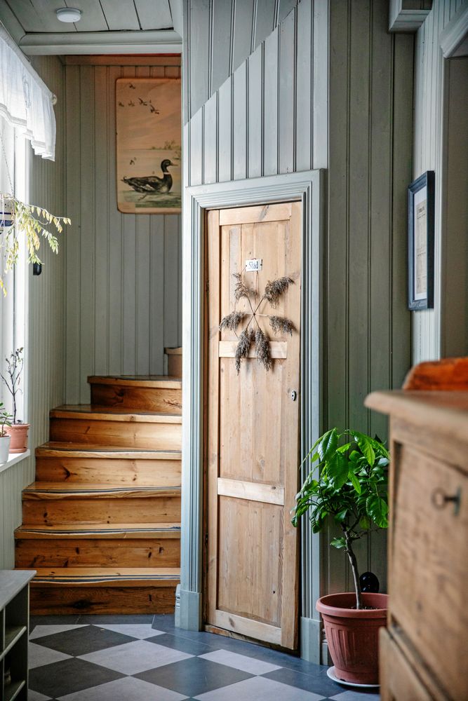 Även hallen har panel målad i milda gröna färger och inbyggd värme i det svartvit-rutiga golvet.