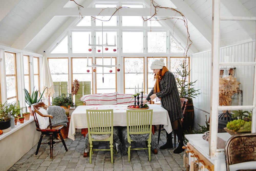 I orangeriet flödar ljuset från fönster ända upp mot det fyra meter höga taket. Sofia pyntar det stora matbordet här.