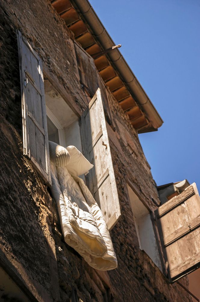 Sängkläder hänger ut genom fönster.