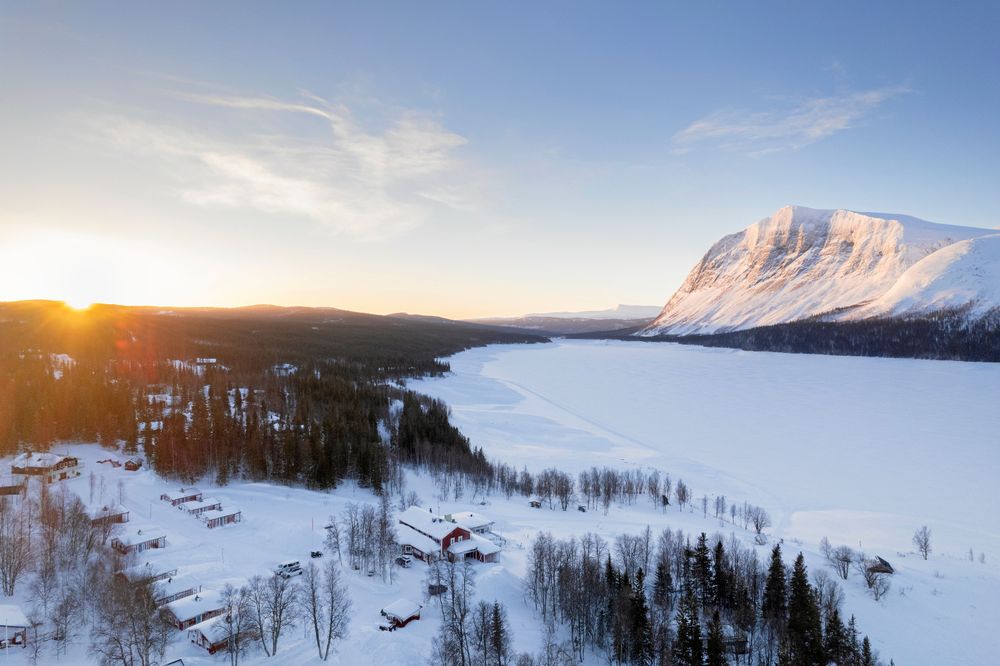 Gästgiveriet och stugorna från ovan, med det mäktiga fjället Borgarhällen i fonden.