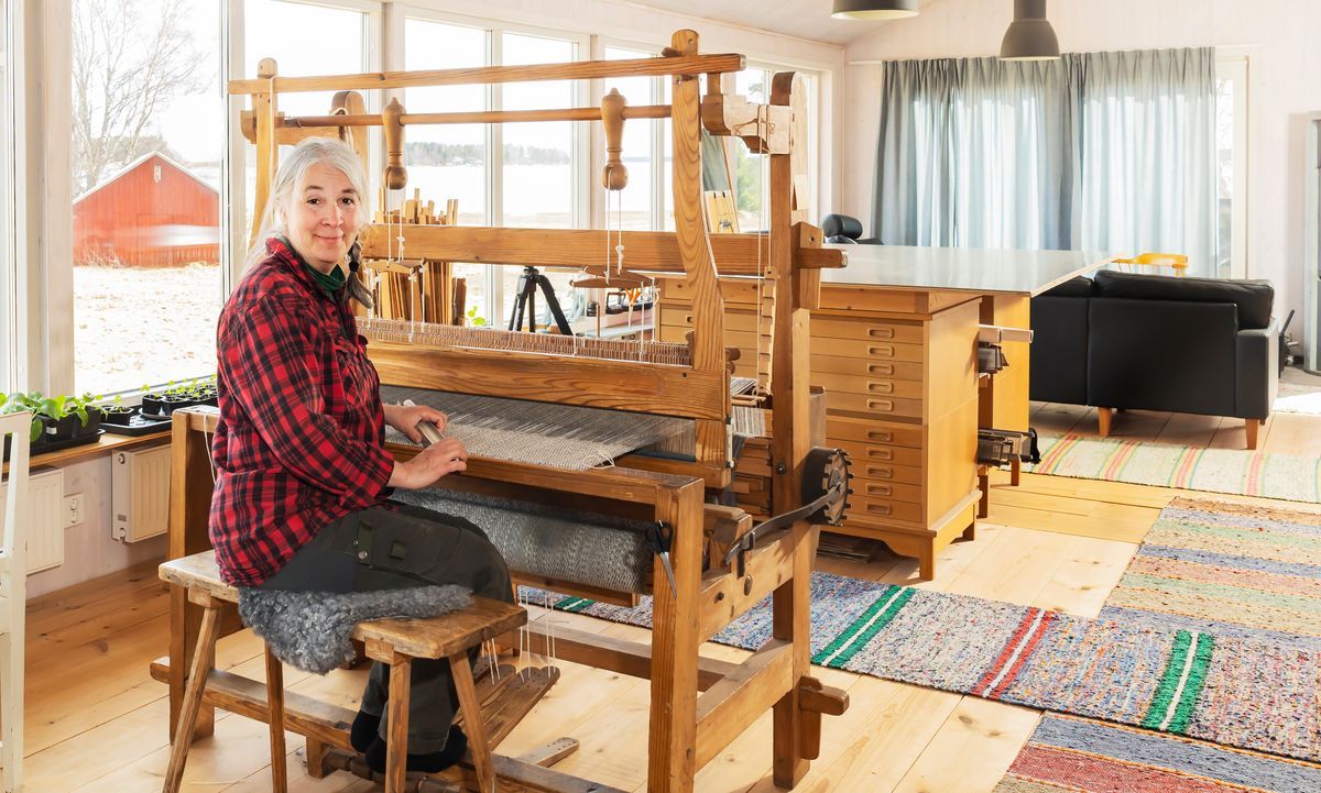 Anna-Carin sitter vid en vävstol och arbetar i ett ljust, hemtrevligt rum