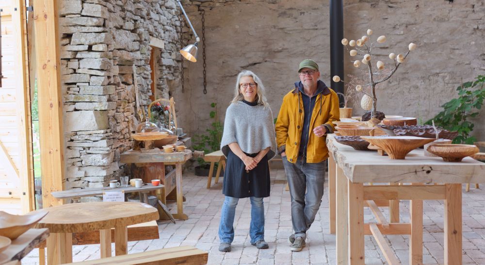 Agneta Green och Magnus Ek i ljus verkstad med utställda träföremål på bord runtomkring
