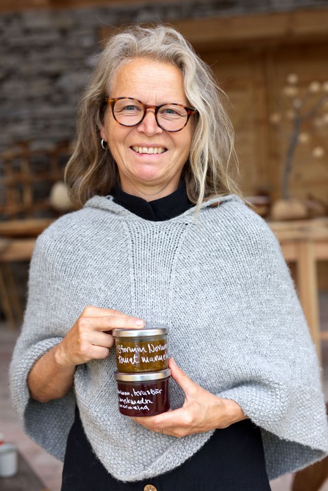 Leende kvinna i glasögon håller en burk hemgjord marmelad