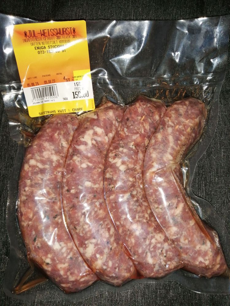 Vacuumförpackade råa korvar i plastförpackning mot mörk bakgrund