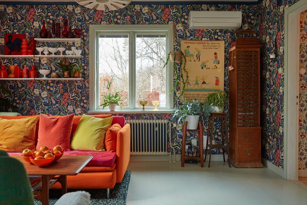 Färgglatt vardagsrum med orange soffa, mönstrade väggar och många växter