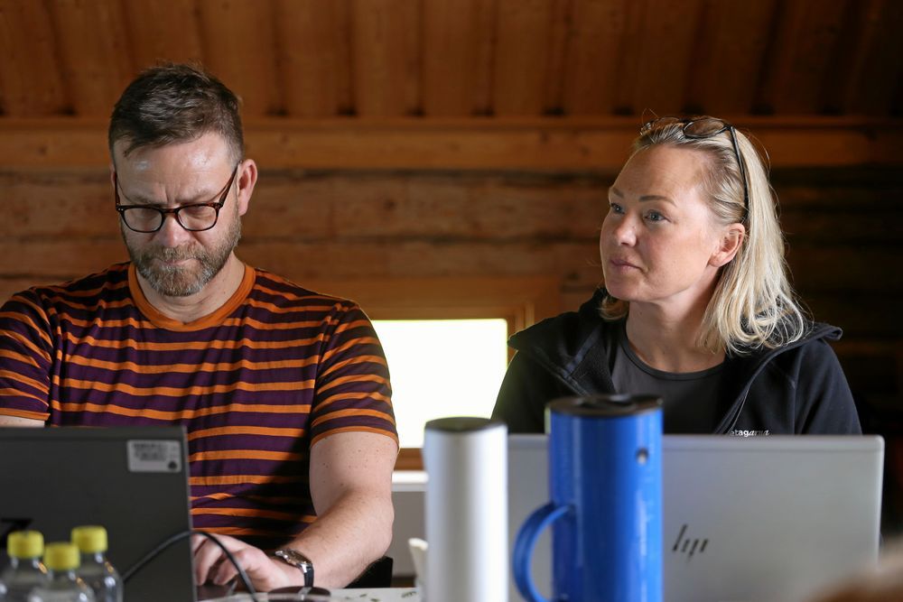 Två personer arbetar vid bärbara datorer inomhus.