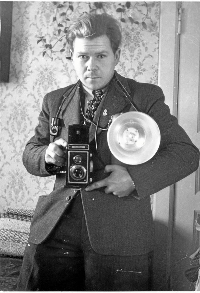 Olof Olsson med sin kamera på magen och en blixtlampa under armen.