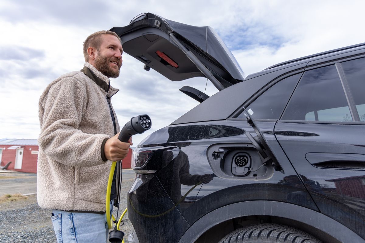 Man laddar elbil med laddkabel vid bakluckan.