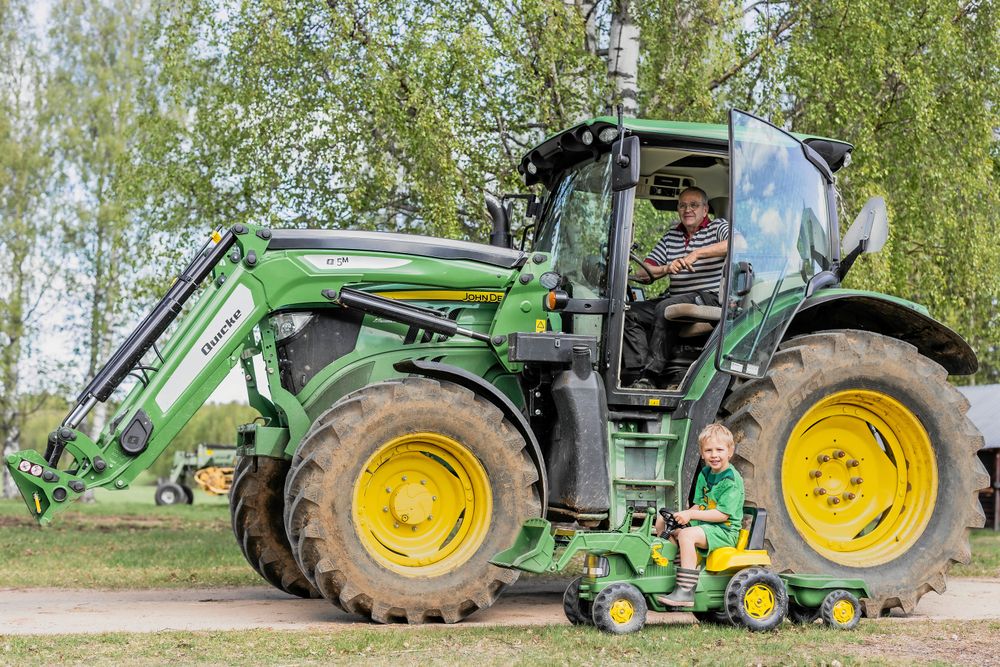 Farfar Gunnar Liljebäck i sin traktor med äldsta barnbarnet Alfred i en minitraktor.