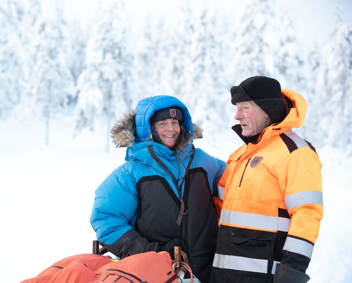 Lina Hallebratt och Johnny Engman i vinterkläder pratar i snöigt, skogigt landskap
