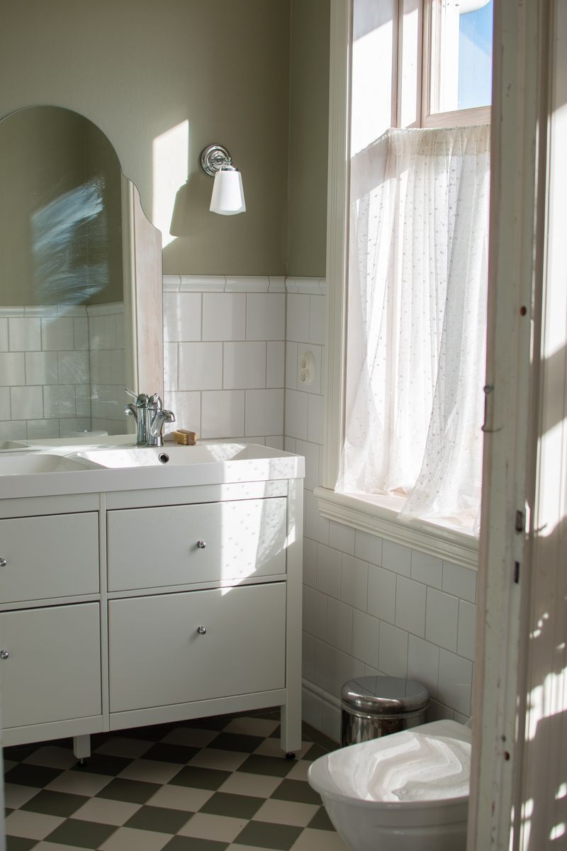Ljust badrum med vit inredning och checkerat golv.