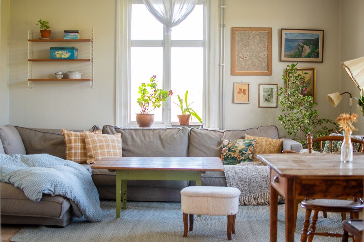 Ljust vardagsrum med konst och gröna växter.