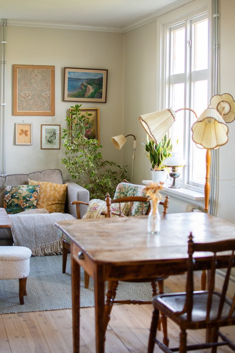 Vardagsrum med vintage-dekorationer och stora fönster.