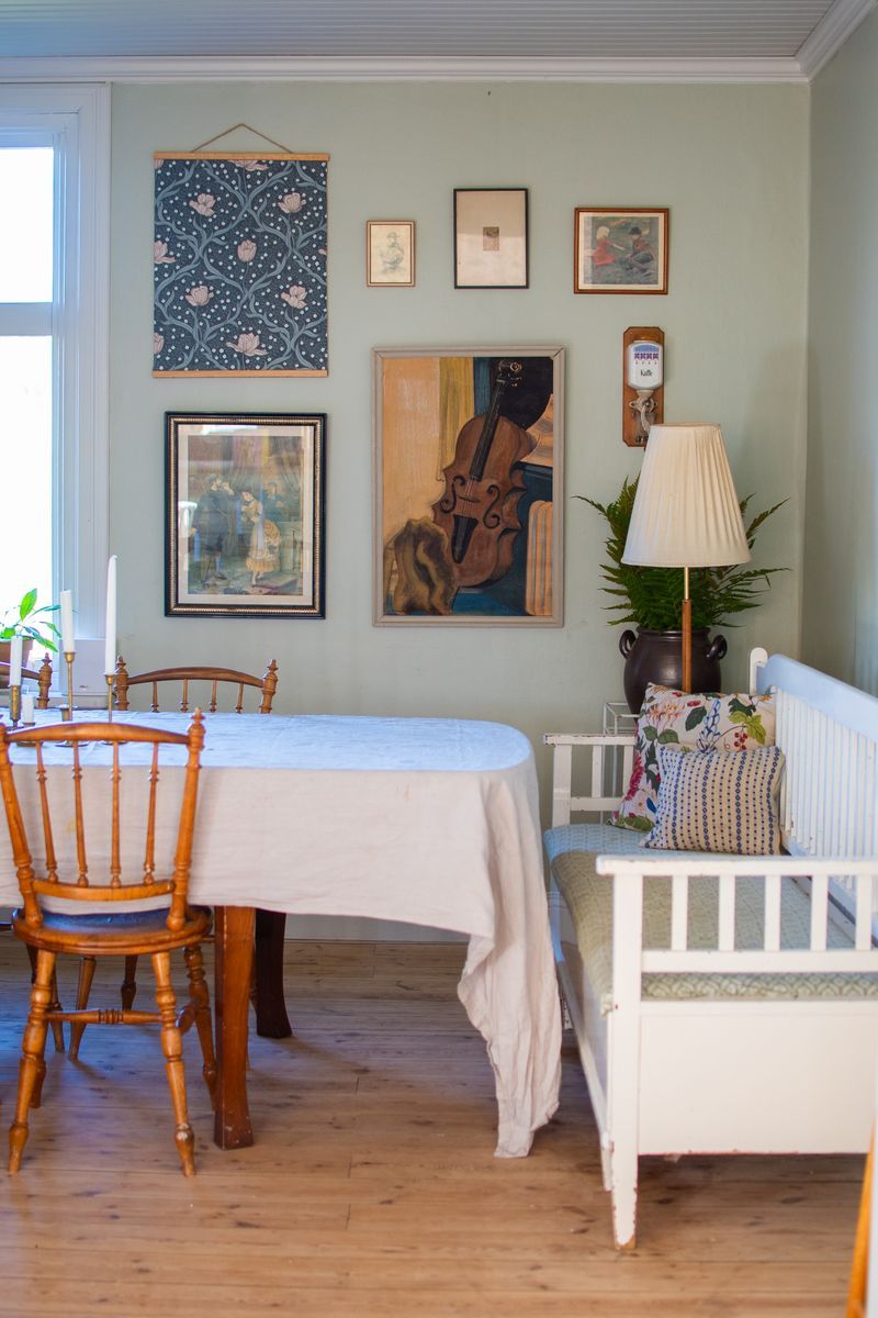 Matbord med duk, stolar, soffa och konst på väggarna.