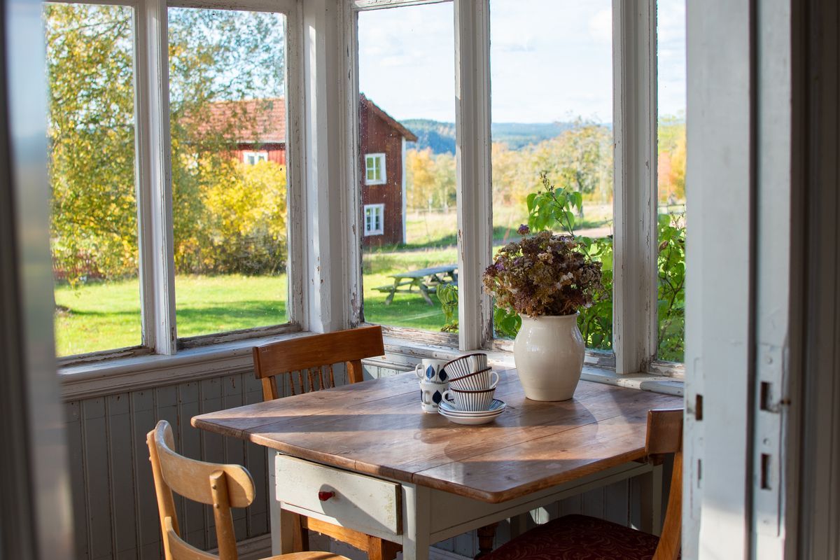 Träbord och blommor i rum med stora fönster.