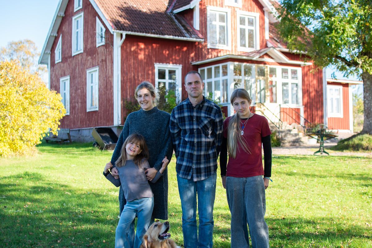 Josefine och Fredrik framför sitt röda trähus i Norrlida med döttrarna Lykke och Jonie och hunden Ester i trädgården.