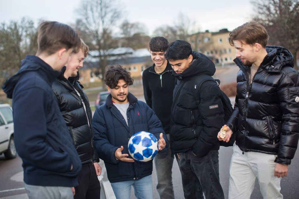 Killarna håller en fotboll utomhus.