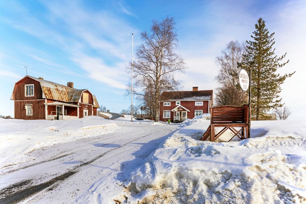 Vintermiljö med lantliga svenska byggnader.
