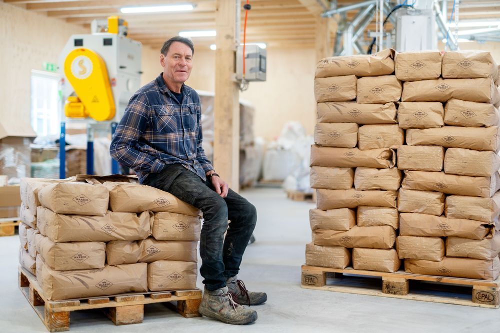 Thomas Björklund sitter på pall med papperssäckar i ljus lagerlokal