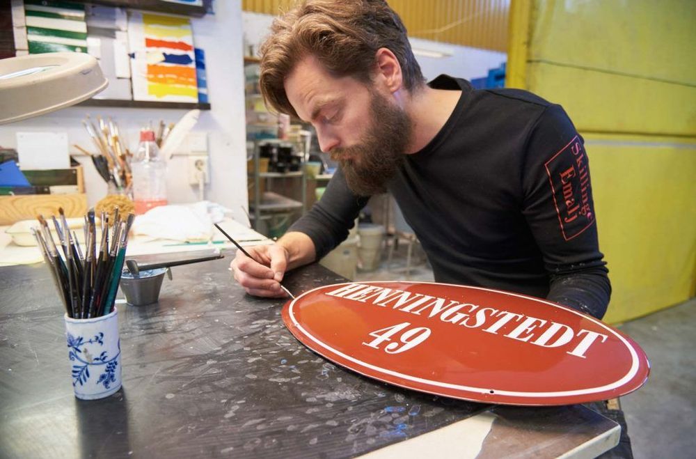 Fredrik Trane gör den sista finjusteringen innan emaljskylten skall in i ugnen.