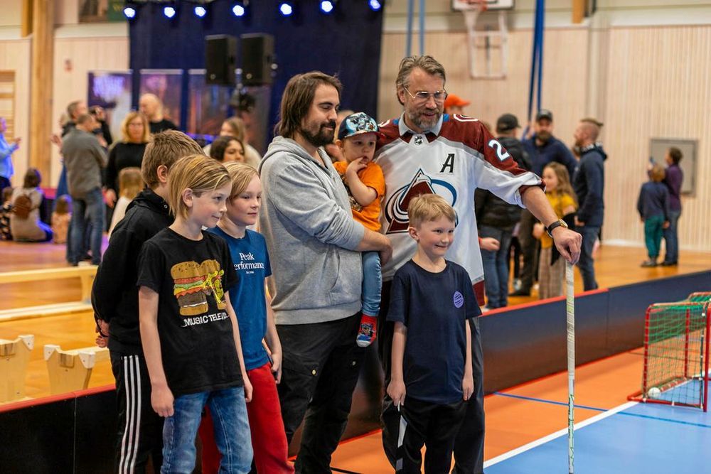 Män och barn poserar vid en bandyrink inomhus.