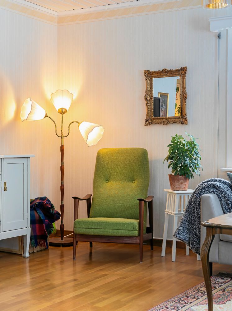 I vardagsrummet står den gröna fåtöljen från den förre ägaren, omgiven av fina loppisfynd.