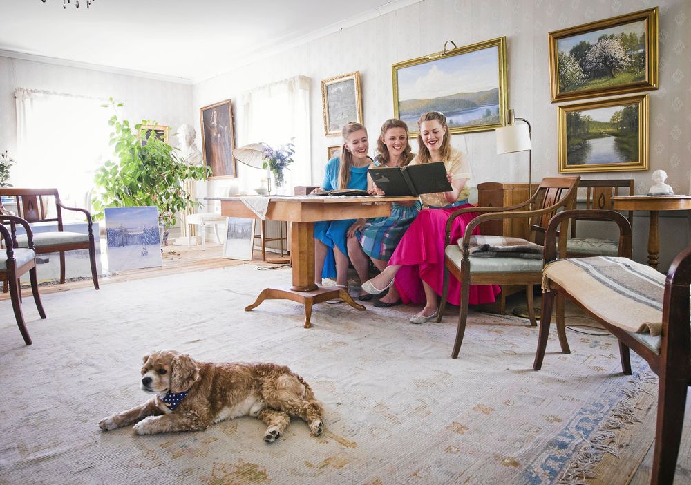 Salongen i huvudbyggnaden sträcker sig över halva övervåningen. Den är full av minnen av tidigare generationen, som det fotoalbumet som Emelie, Josefine och Maria tittar i. Hunden Bobby i förgrunden.