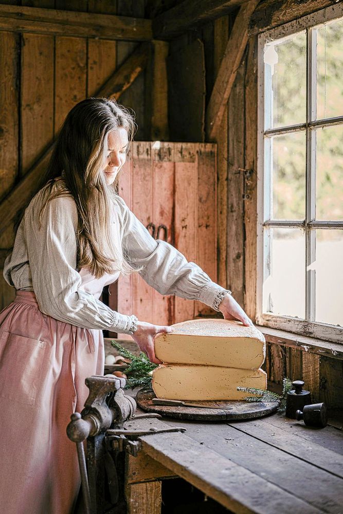 Olivia skär upp en bit Lillebackeost i den gamla smedjan på ett av fotona hon använder på sociala medier bland annat.