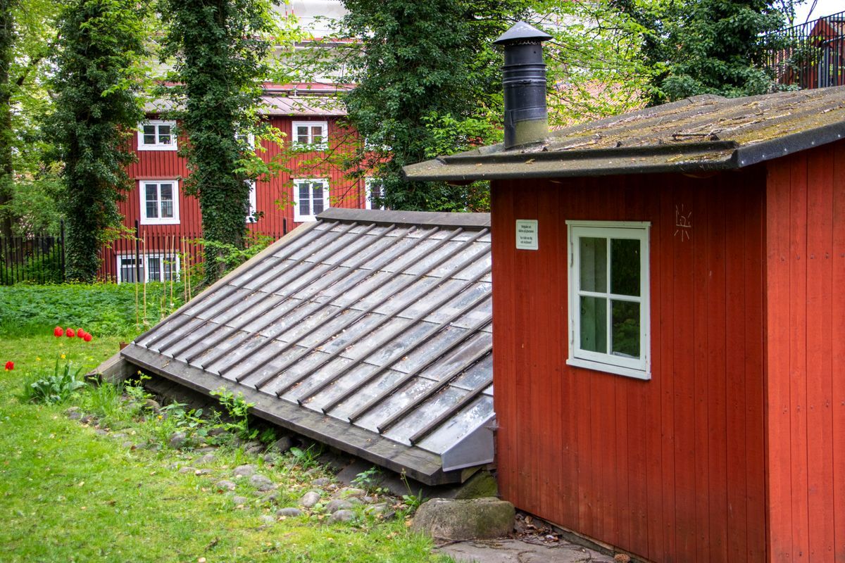 Litet rött hus med plåttak, till ett orangeri.