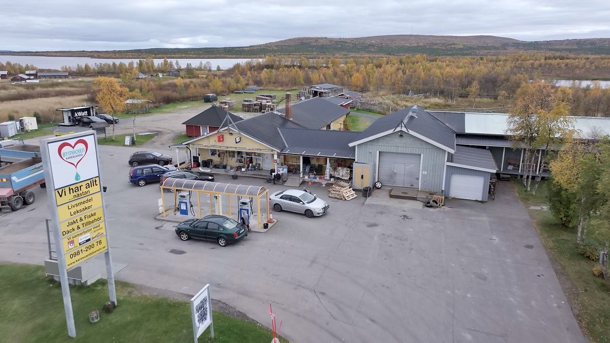 Macken i Karesuando med bensinpump, bilar och höstlandskap med sjö i bakgrunden.