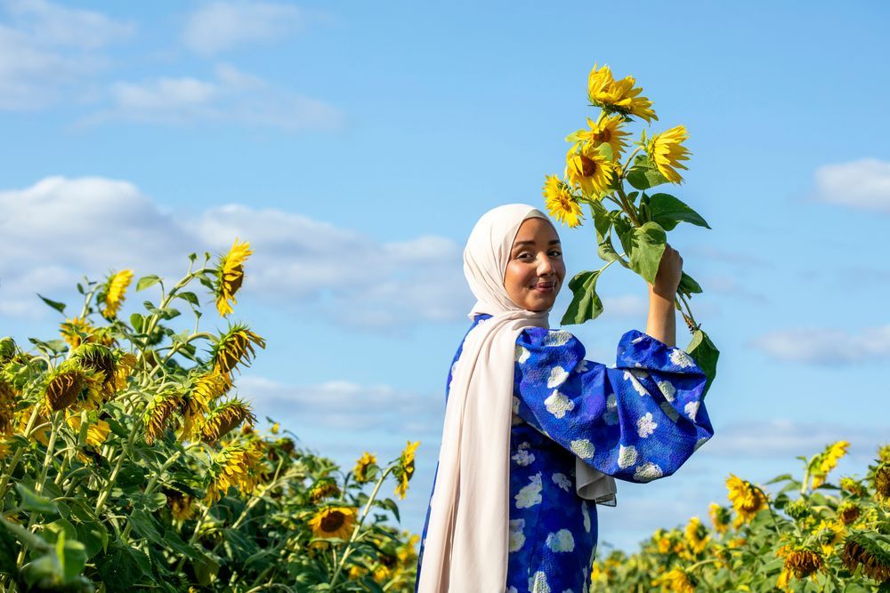 Camilla Hamid håller upp solros på solrosfält.