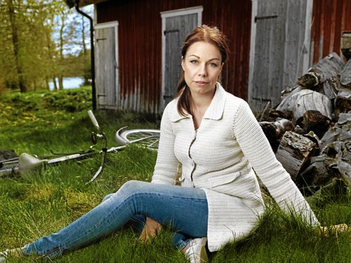 Lina Bengtsdotter bakom handelsboden i Gullspång, samhället där hon växte upp och nu börjat använda som deckarmiljö.